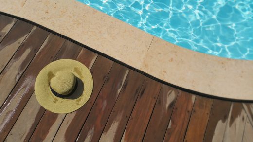 chapeau de paille posé à côté de la margelle de la piscine